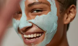 Glad person med lermask som rengör porer.