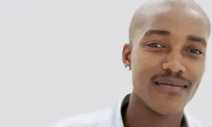 En ung man med rakad skalle och en diskret mustasch som han verkar vara nöjd med att trimma.