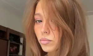 En ung kvinna med hår som skiftar från blond till brunett, med en mjuk blick.