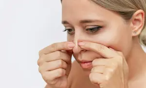 Kvinna undersöker sin näsa, kanske funderar på hur man får bort pormaskar.