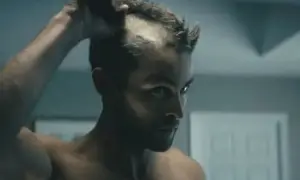 Man raka huvudet i spegeln, med en intensiv blick.