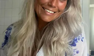 Glad kvinna med blont, vågigt hår som vill få rakt hår utan plattång. Hon ler och har en blåvit blommig klänning.