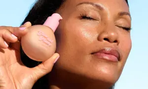 En hand håller en flaska "Glow and Plump" hudserum. Ansiktet visar en naturlig glow up med glansiga läppar.