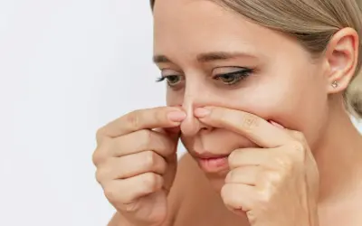 Kvinna undersöker sin näsa, kanske funderar på hur man får bort pormaskar.