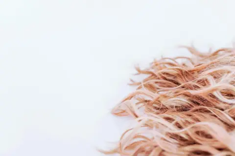 Lockigt, blont hår som ser ut att ha fått en behandling med hair botox för extra glans och mjukhet.