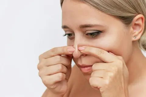 Kvinna undersöker sin näsa, kanske funderar på hur man får bort pormaskar.
