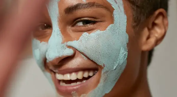 Glad person med lermask som rengör porer.