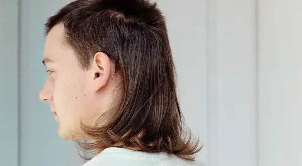 Profilbild på en person med en modern mullet. Håret är kortklippt upptill och längre baktill, med en mjuk övergång.