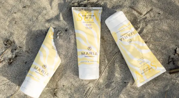 Tre tuber med solskydd från MARIA ÅKERBERG ligger på sanden. Solkrämen har SPF 30 och innehåller zinkoxid samt aloe vera.
