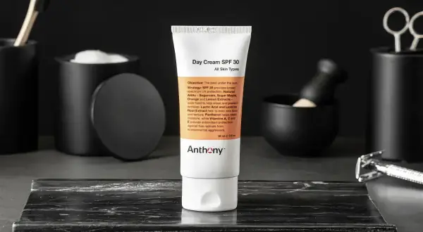 En tub med dagkräm SPF 30 från Anthony står i fokus. Runtomkring syns accessoarer som en rakhyvel och borste, vilket antyder en komplett hudvårdsrutin ordning.