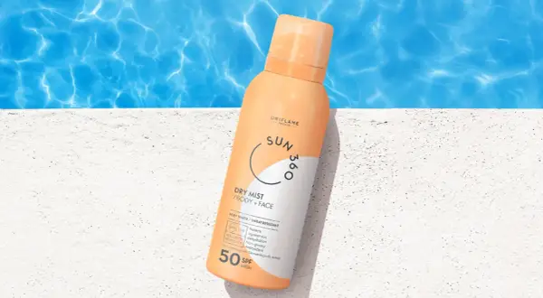 En sprayflaska med solskyddsfaktor 50 står på en vit yta vid en pool. Perfekt för att skydda mogen hy mot solen.