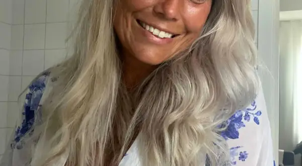 Glad kvinna med blont, vågigt hår som vill få rakt hår utan plattång. Hon ler och har en blåvit blommig klänning.