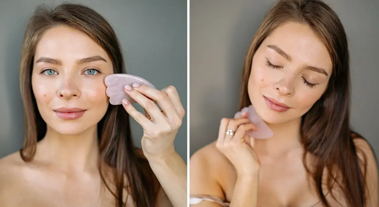 Kvinna använder en rosa gua sha sten för ansiktsmassage.