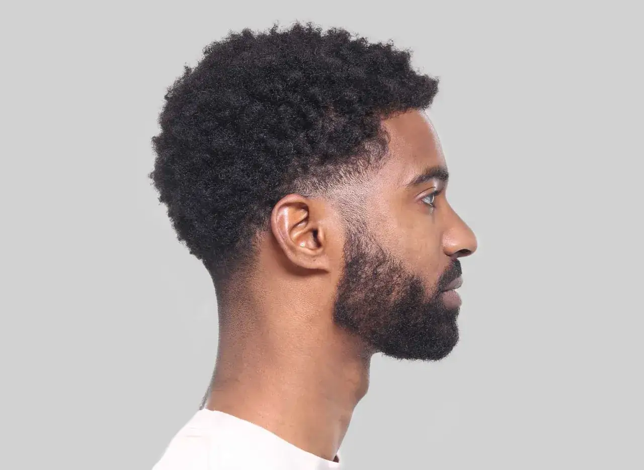 Man med afro och skägg, med en snygg taper fade frisyr.
