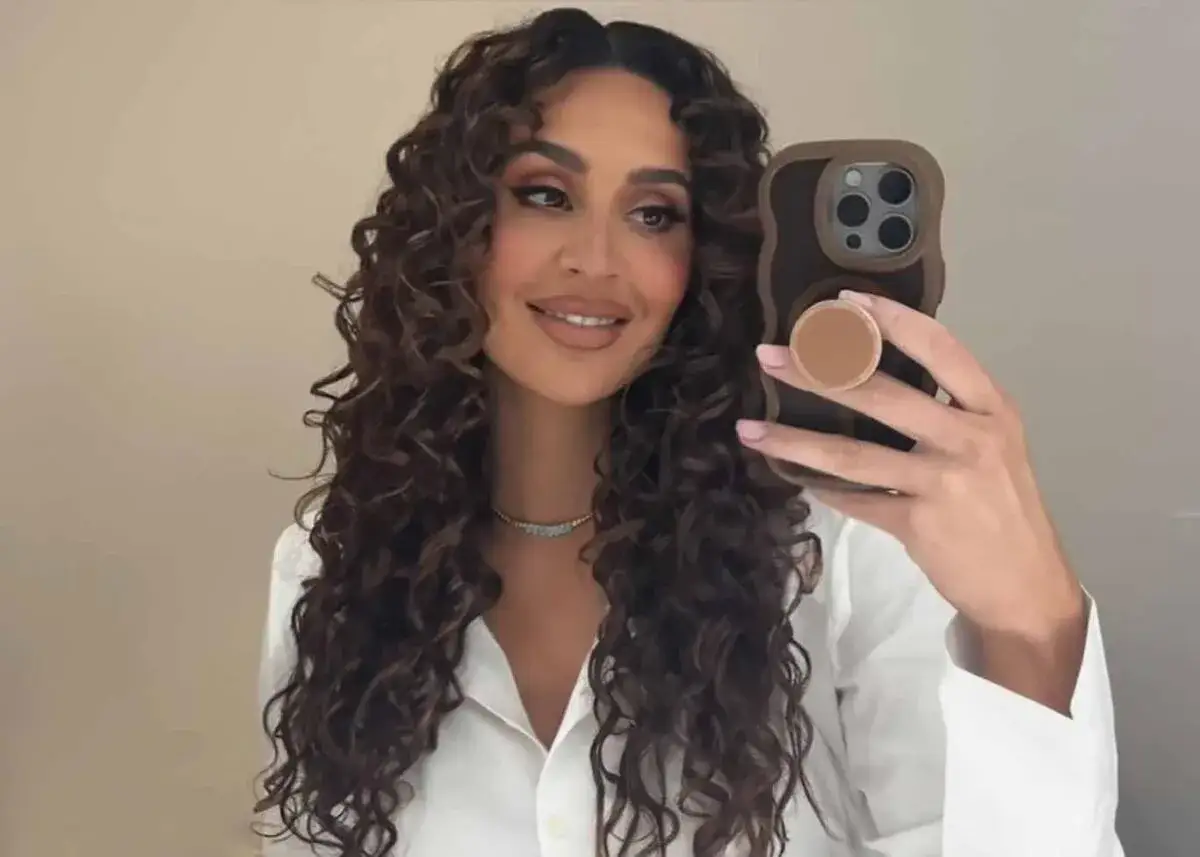 Kvinna med vackert lockigt h&aring;r, ett resultat av curly girl method, tar en selfie.
