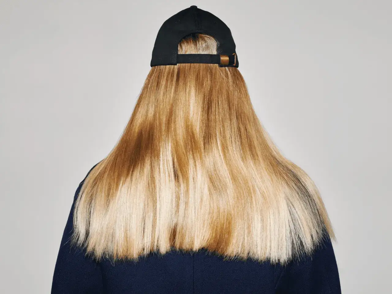 En person med l&aring;ngt, blont h&aring;r och en svart keps. H&aring;ret har en naturlig glans, som om det vore l&auml;tt att ljusa upp h&aring;ret utan blekning.