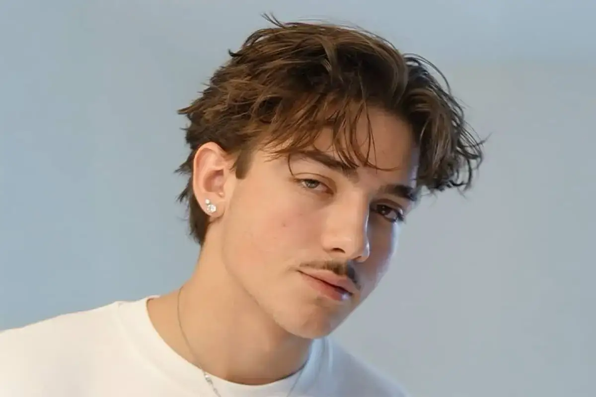En ung, stilig mittbena kille med en diskret mustasch och en &ouml;rh&auml;nge.