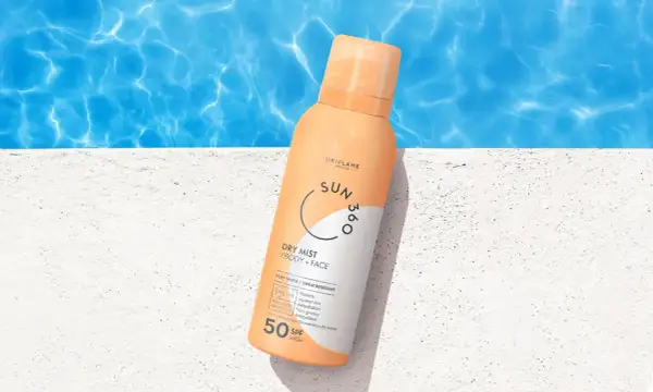 En sprayflaska med solskyddsfaktor 50 står på en vit yta vid en pool. Perfekt för att skydda mogen hy mot solen.